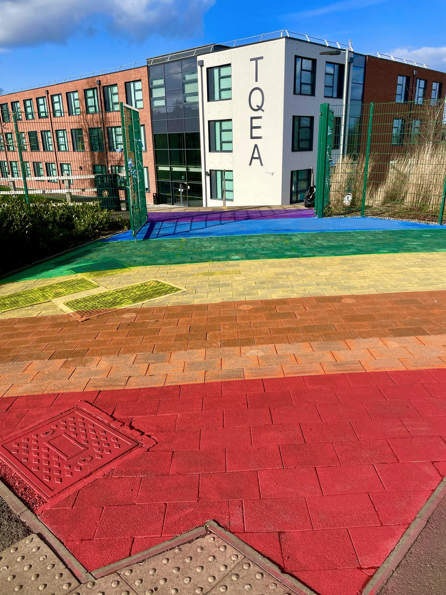 Picture of the front entrance of The Queen Elizabeth Academy in Atherstone. The front of the school has a large rainbow paint